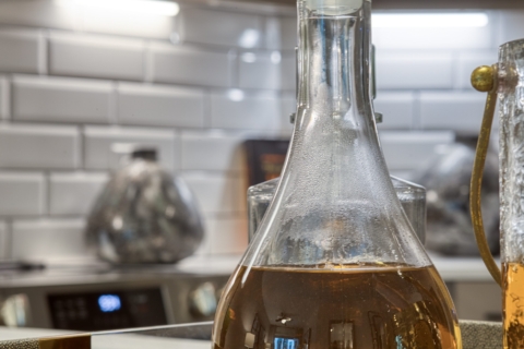 Close up shot of oil and vinegar bottles in a kitchen with white subway tile backsplash